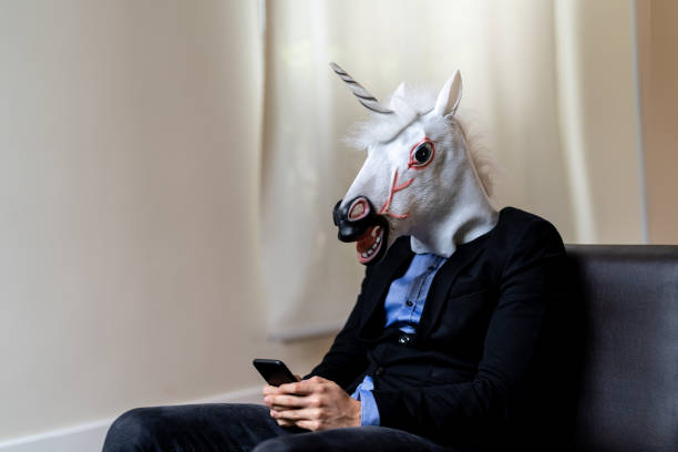 istock Business man with Unicorn Mask Using Mobile at Office 947517302