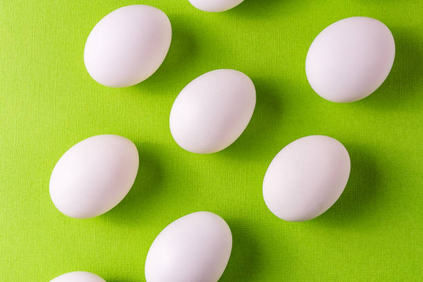 istock Organic white eggs in a raw on green paper backgound. 947521876