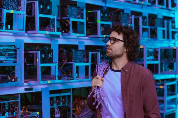 handsome computer engineer with wires on shoulder at ethereum mining farm