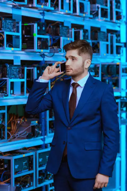 handsome young businessman talking by phone at ethereum mining farm