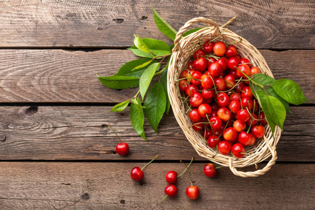 istock Cherry. Fresh sweet cherry with leaves in basket on wooden table 947527092
