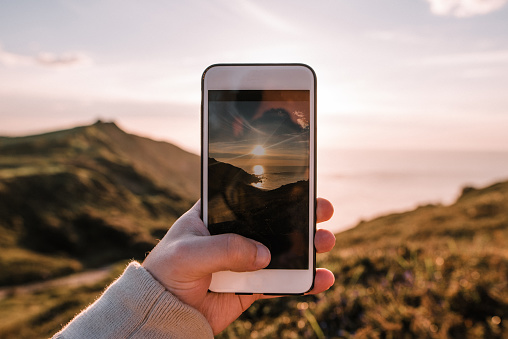 Taking a picture of the sea at sunset with a mobile phone