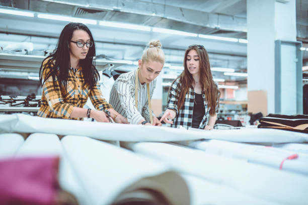 istock Young Fashion Designers Talking About Layout and Measure the Material 947548028