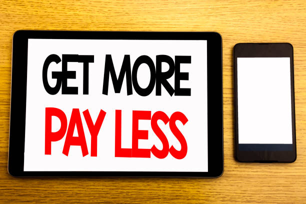 istock Writing text showing Get More Pay Less. Business concept for Budget Slogan Concept Written on tablet laptop, wooden background with sticky note, coffee and pen 947549838