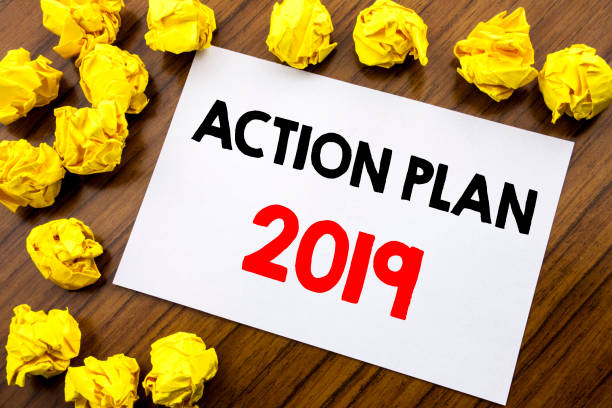 istock Handwritten text showing word Action Plan 2019. Business concept writing Success Strategy Written on sticky note paper, wooden background with space office view with folded yellow paper 947553816