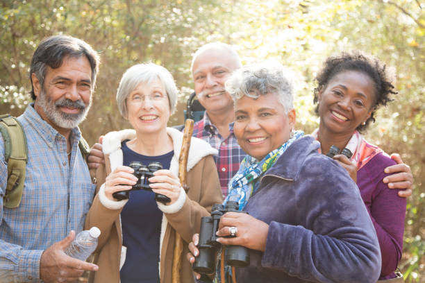 multi-ethnic, active senior adult friends hiking in wooded forest area. - indiana autumn woods forest imagens e fotografias de stock