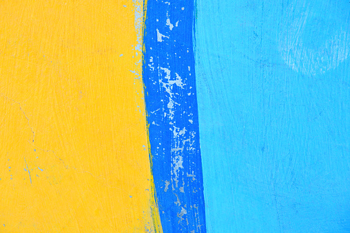 Concrete wall painted in colors of yellow and blue. Close up for background.