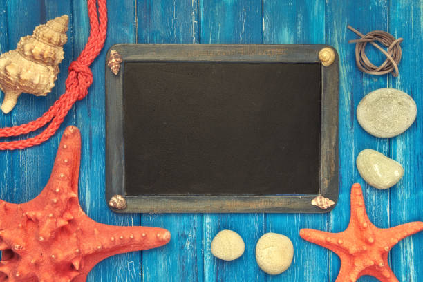 istock Blank blackboard with sea shells, rope and star fish on blue wood, copy-space 947574670