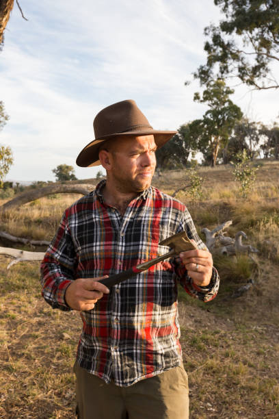 istock Farmer in red flannel shirt holding axe stares into sunset 947577228