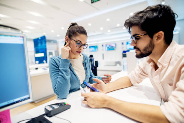 istock Beautiful young brunette talking with employe in the tech store. 947580986