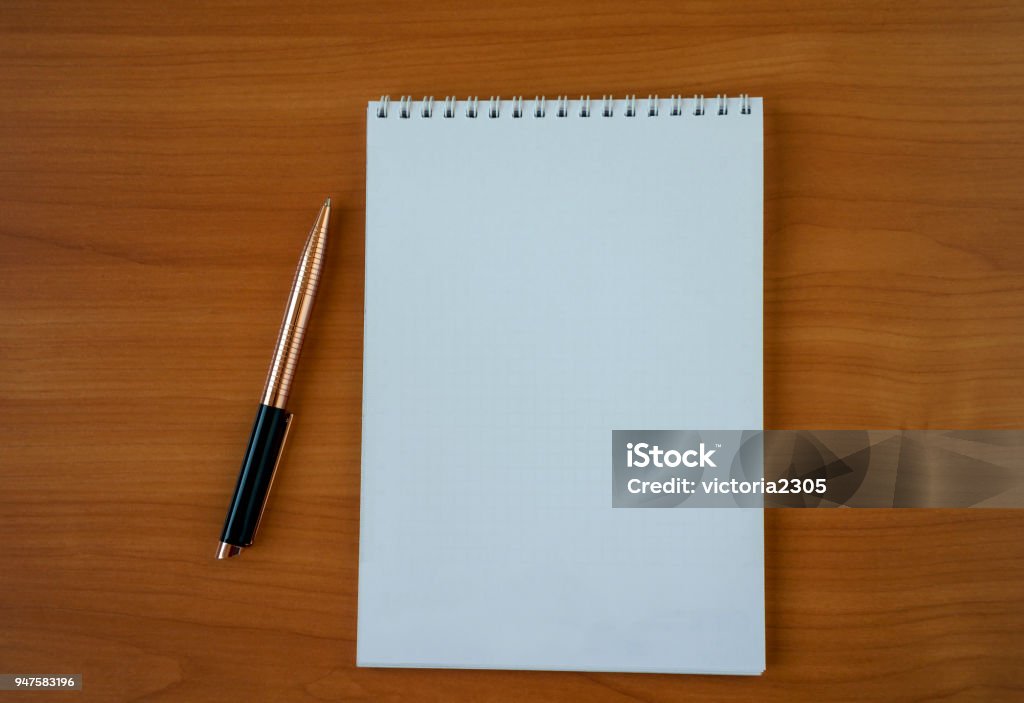 Notepad with pen White notebook for notes with a pen on a bright wooden background, close-up Aspirations Stock Photo