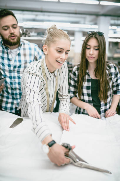 istock Cute Smiling Tailor is Making New Shirt Samples with Her New Colleagues 947583682