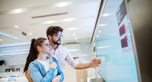istock Joyful young attractive multiracial couple checking out plasma TVs in the electronic store. 947584190