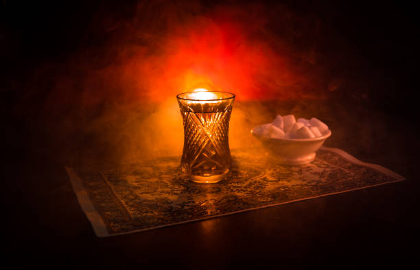 istock Eastern tea in traditional glasse and pot on black background with lights and smoke. Eastern tea concept. Armudu traditional Azerbaijan/Turkish cup 947597992