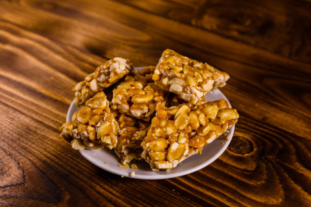 istock Ceramic plate with peanut brittles on wooden table. 947645132