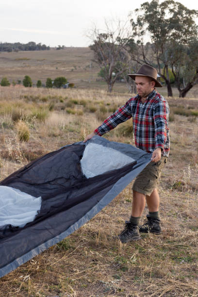 istock Man setting up his tent in a flat section of ground with sunset behind him 947655952
