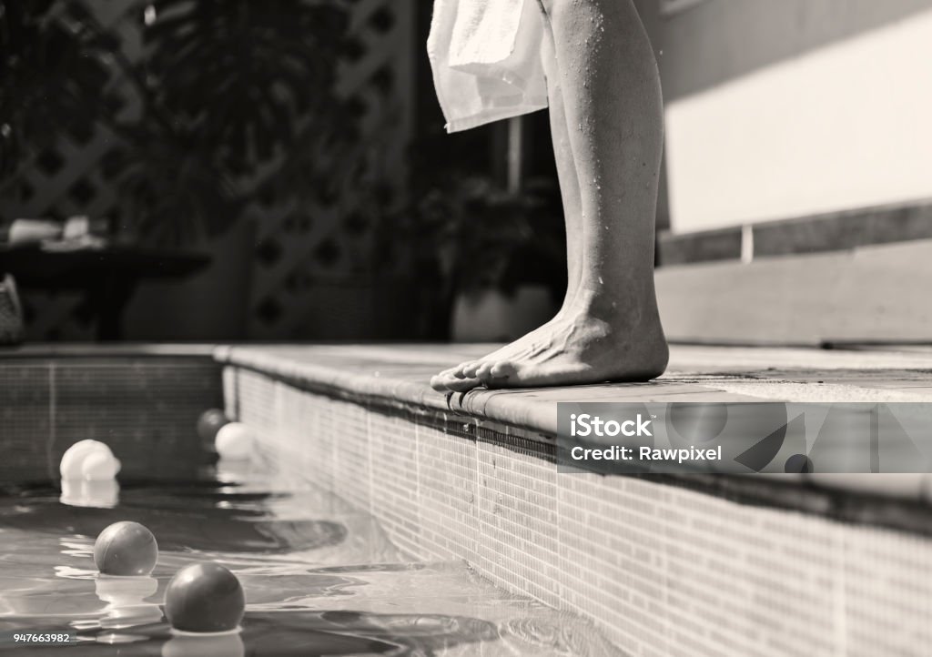 Woman standing by a swimming pool Black And White Stock Photo