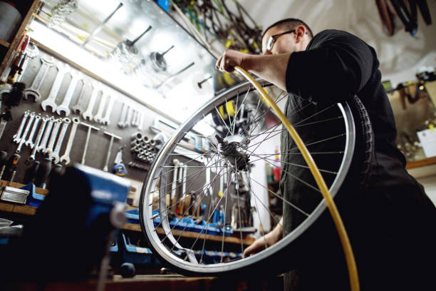 istock Young professional man preparing to pump air into bicycle wheel. 947664354