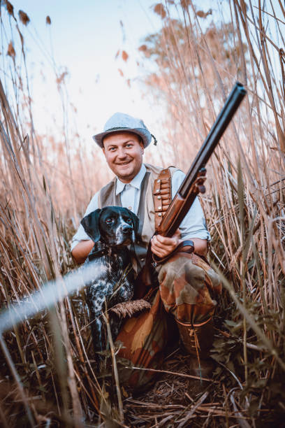 istock Smiling Hunter with his Dog Hiding in the Reed 947664368