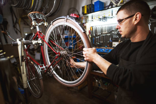 istock Professional young man checking bicycle wheel and wires. 947664662