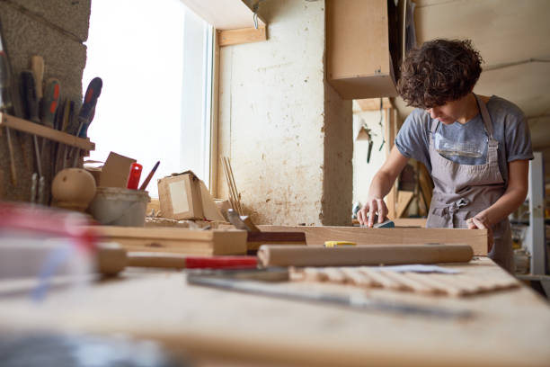 istock Busy wood carving master cleaning plank from dust 947667660