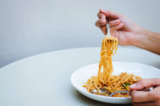 istock spaghetti pasta delicious with hands using forks and spoons eating on the table. 947682240