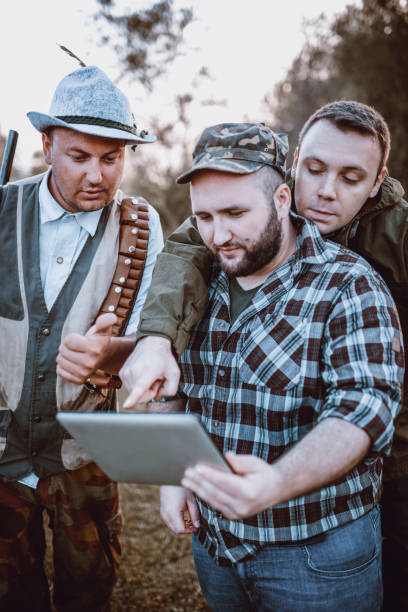 istock Group of Hunters Looking for GPS Coordinates on Tablet in Nature 947683530