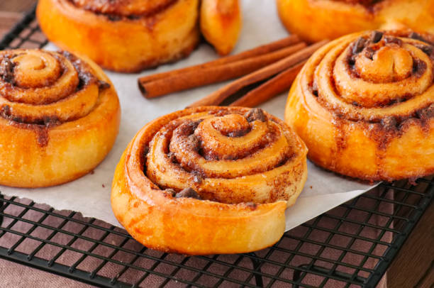 istock Classic cinnamon rolls - cinnabons won a wire rack. Wooden background. 947685844