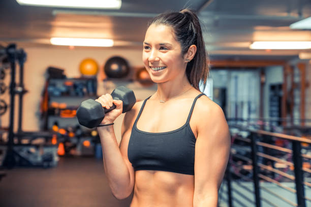 istock Attractive young woman lifting weights at the gym 947690892