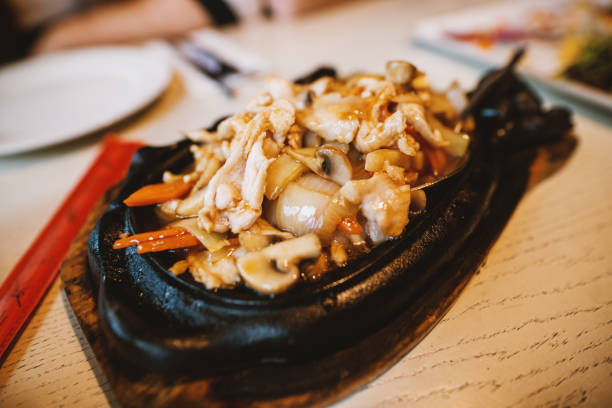レストランで中華料理を食べながら箸で肉を持っている女性の手のビューを閉じます。