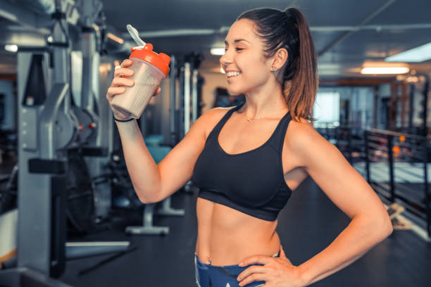 istock Attractive young woman drinking protein shake at gym 947695432
