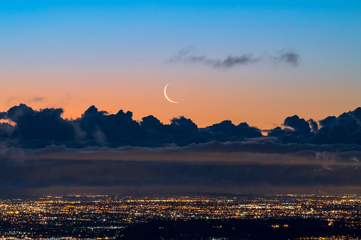 Crescent moon rising above clouds over Los Angeles at dawn