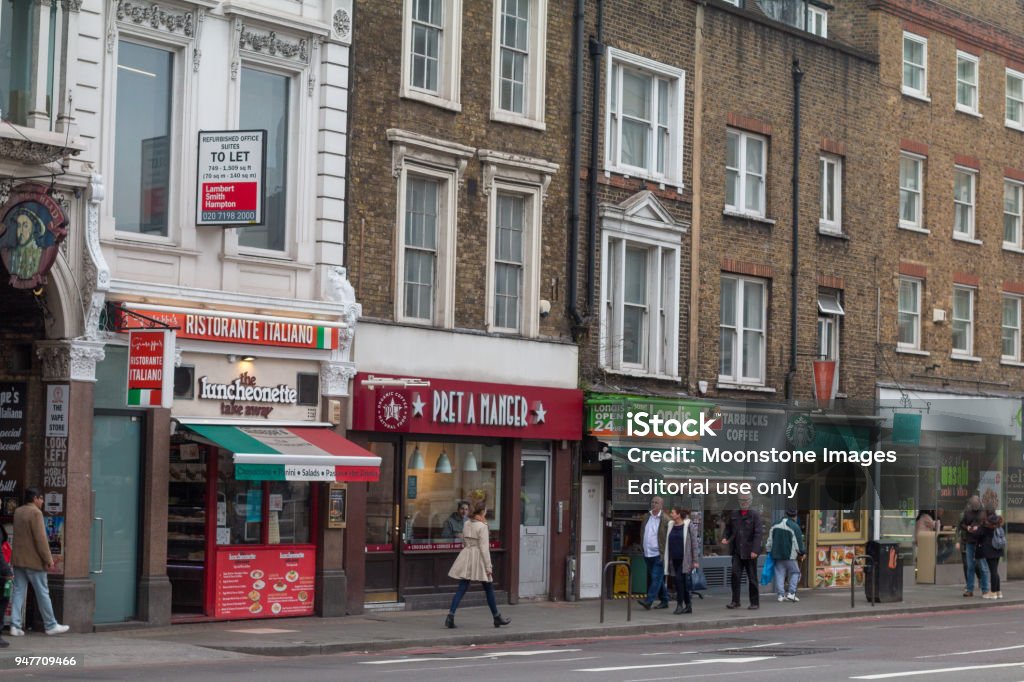 Pret a Manger on The Strand, London Several shop-fronts on the Strand including the food chain Pret a Manger. Also visible is Londis, Starbucks Coffee and an Italian restaurant. People are walking past. Architectural Feature Stock Photo