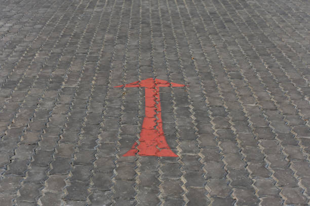 istock Arrow red sign paint on a brick road or walkway 947714424