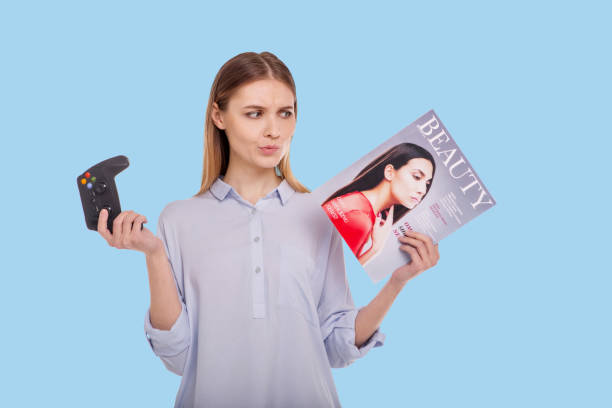 istock Cheerful woman choosing between magazine and video game 947720982