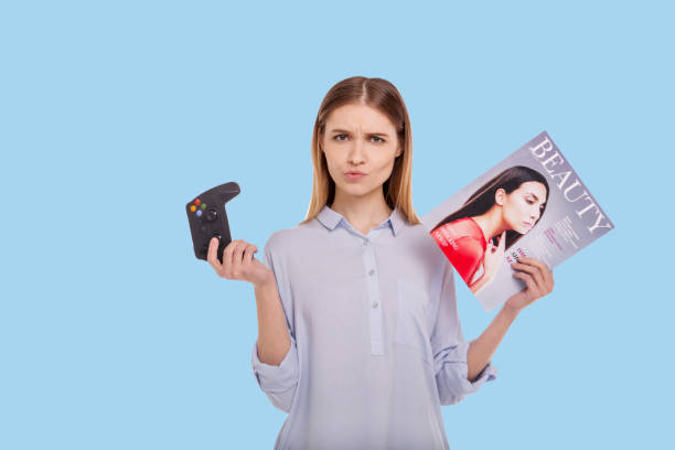 istock Petite woman making choice between gaming and reading magazine 947721052