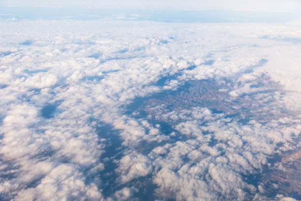 Wing of an airplane flying above the clouds with blue sky. View at the sky from the window of the plane.