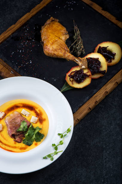 istock An appetizing pumpkin soup is served in a white plate in a restaurant. Duck confit with baked apple 947722068