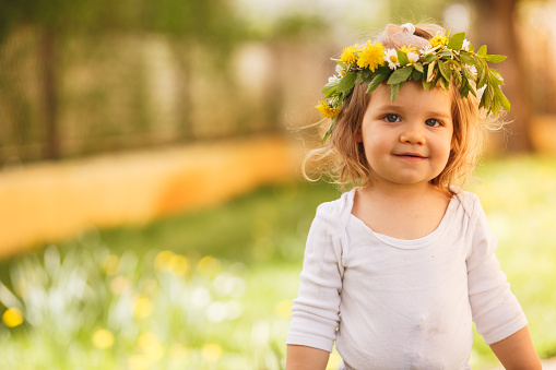 Copy space shot of a smiling toddler girl wearing a beautiful wreath made of fresh wildflowers.
