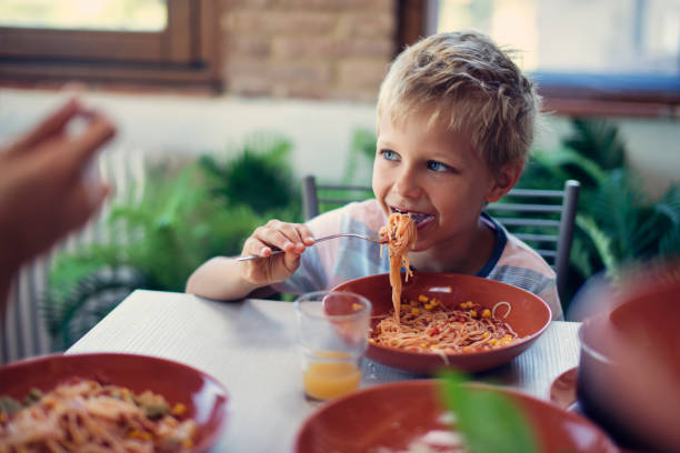 petit garçon manger le dîner spaghetti - child eating pasta spaghetti photos et images de collection