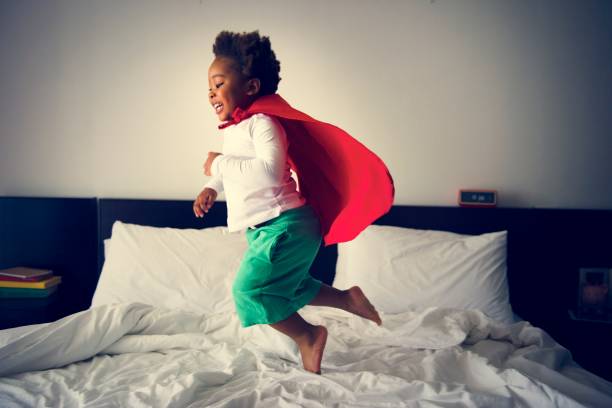 istock African descent kid jumping on the bed with robe 947734834