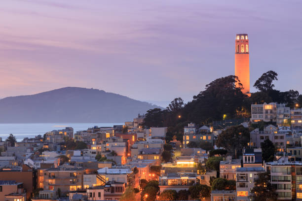 la torre coit en telegraph hill con bahía de san francisco y la isla del ángel en el fondo al atardecer. - tower coit tower san francisco bay area san francisco county fotografías e imágenes de stock