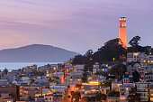 Coit Tower on Telegraph Hill with San Francisco Bay and Angel Island in the background at dusk.
