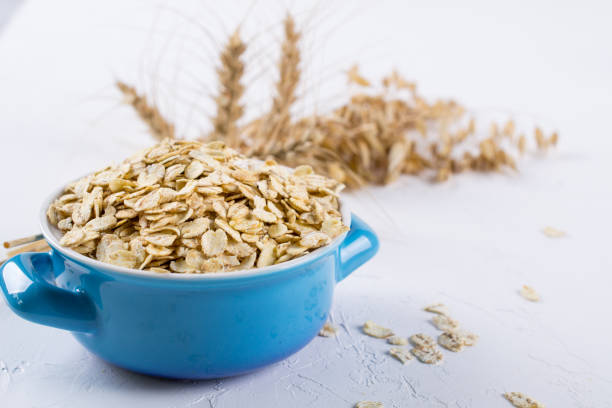 Oat flakes in blue bowl on the kitchen table. Healthy breakfast concept. Oat flakes in blue bowl on the kitchen table. Healthy breakfast concept. bran flakes stock pictures, royalty-free photos & images