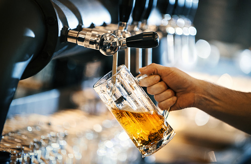 Closeup side view of unrecognizable bartender pouring beer from a tap at a beer cafe.
