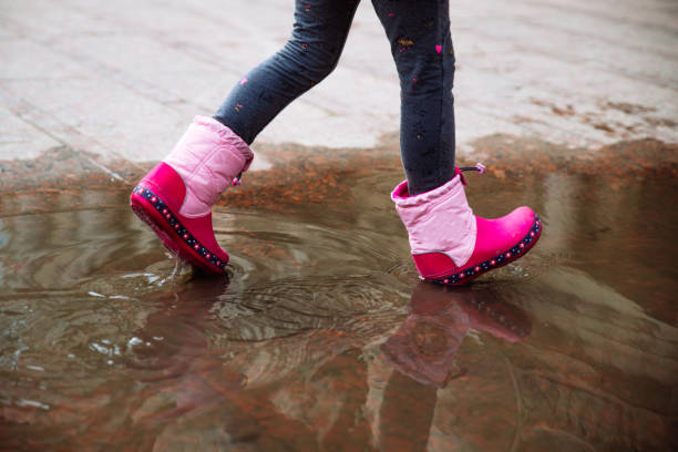 istock little girl in pink rubber boots in puddle. 947748396