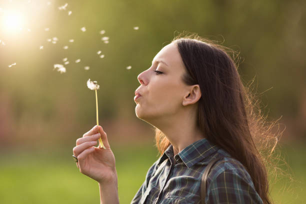 istock Woman blowing dandelion in park 947749496