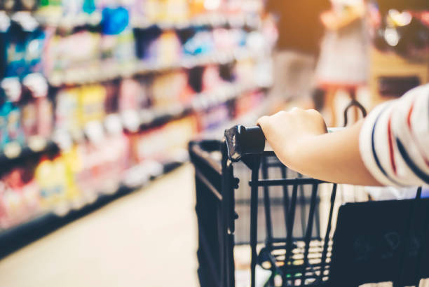 istock Asian woman's hand with supermarket, trolley and many objects that are blurred background. 947767354