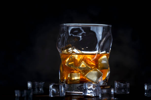 istock Alcohol in glass with ice on dark background 947768398