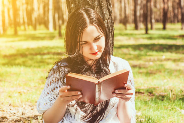 istock Woman relaxing reading book at park 947771390